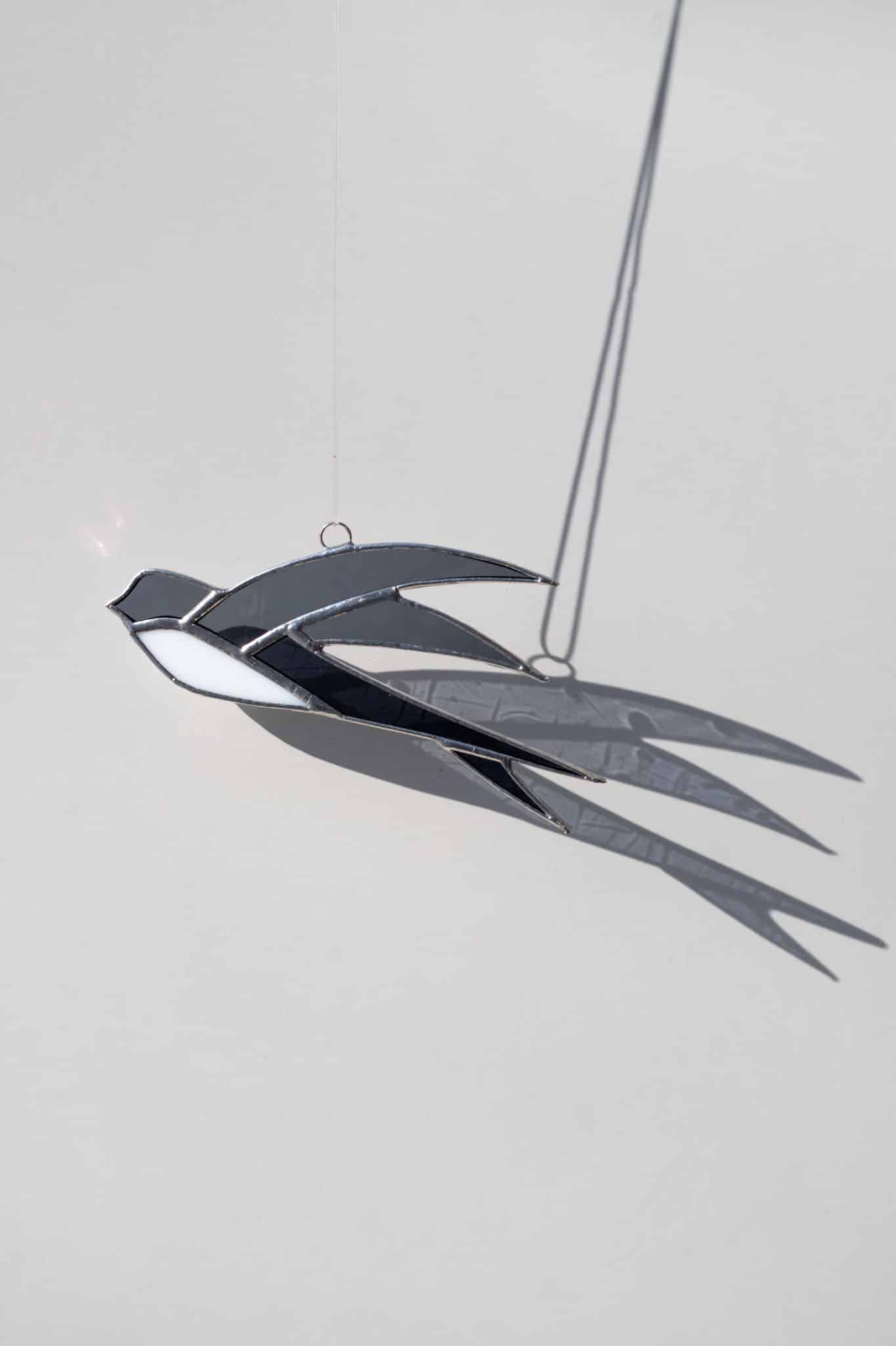 Ručne vyrobená vitrážová dekorácia v tvare letiacej lastovičky zavesená v okne